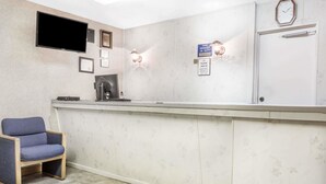 A reception area with a flat-screen TV, framed certificates, a clock, and a sign indicating the manager is on duty. - Travelodge by Wyndham La Grande (La Grande)