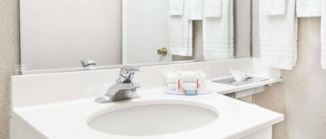 A modern bathroom with a white sink, a mirror, and a towel rack with multiple towels.