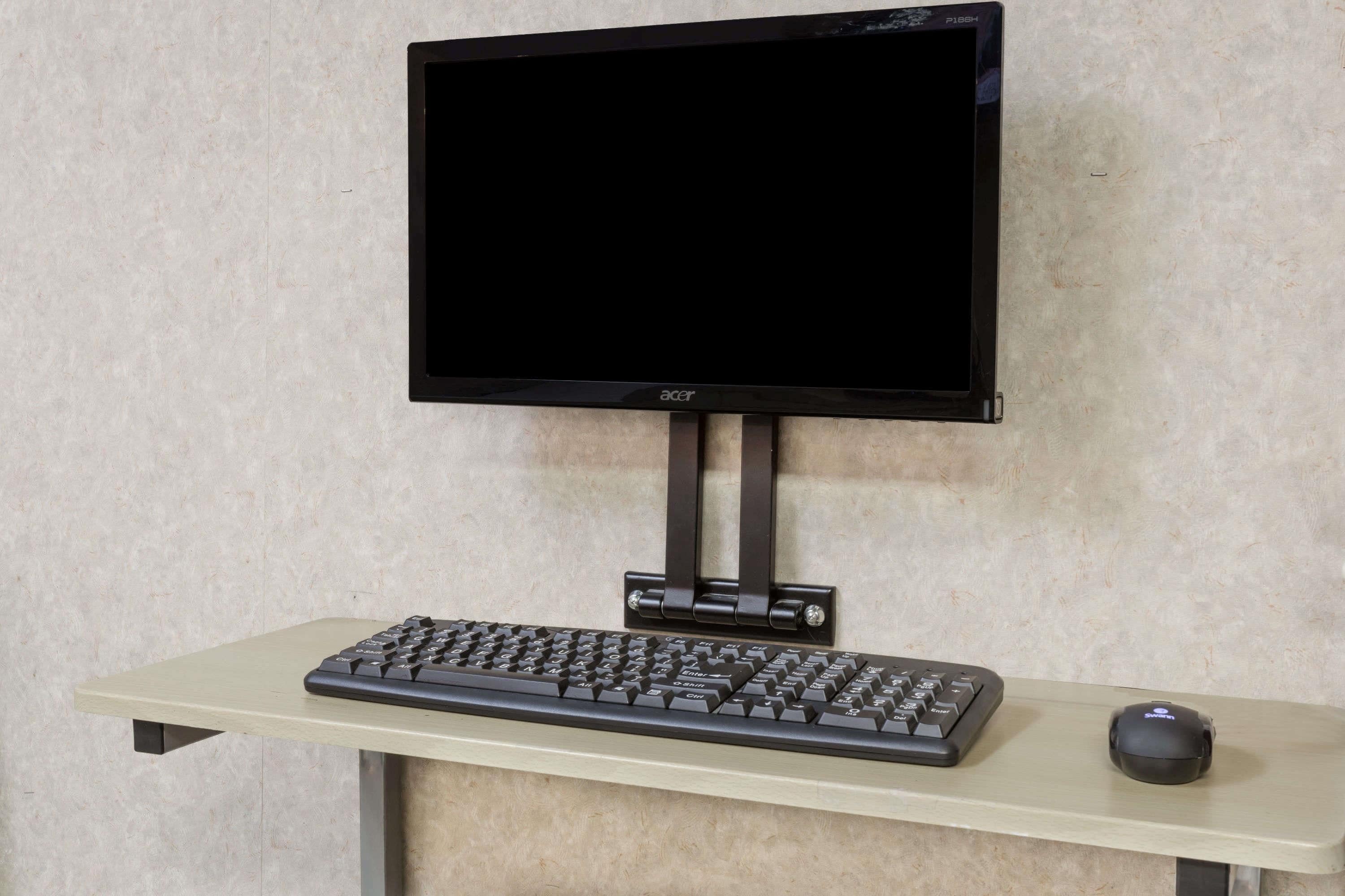 A monitor mounted on a stand, a keyboard, and a mouse on a desk.