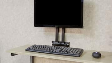 Un monitor sobre un soporte, un teclado y un ratón en un escritorio.