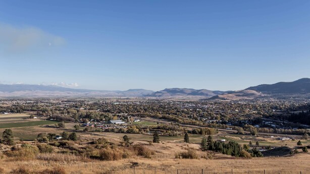 A panoramic view of a town with a mix of residential and commercial buildings, surrounded by open fields and distant mountains. - Travelodge by Wyndham La Grande (La Grande)