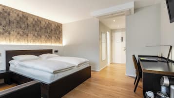 Una habitación de hotel moderna con una cama grande, un escritorio y una silla. El suelo es de madera y hay una decoración de pared de gran tamaño.