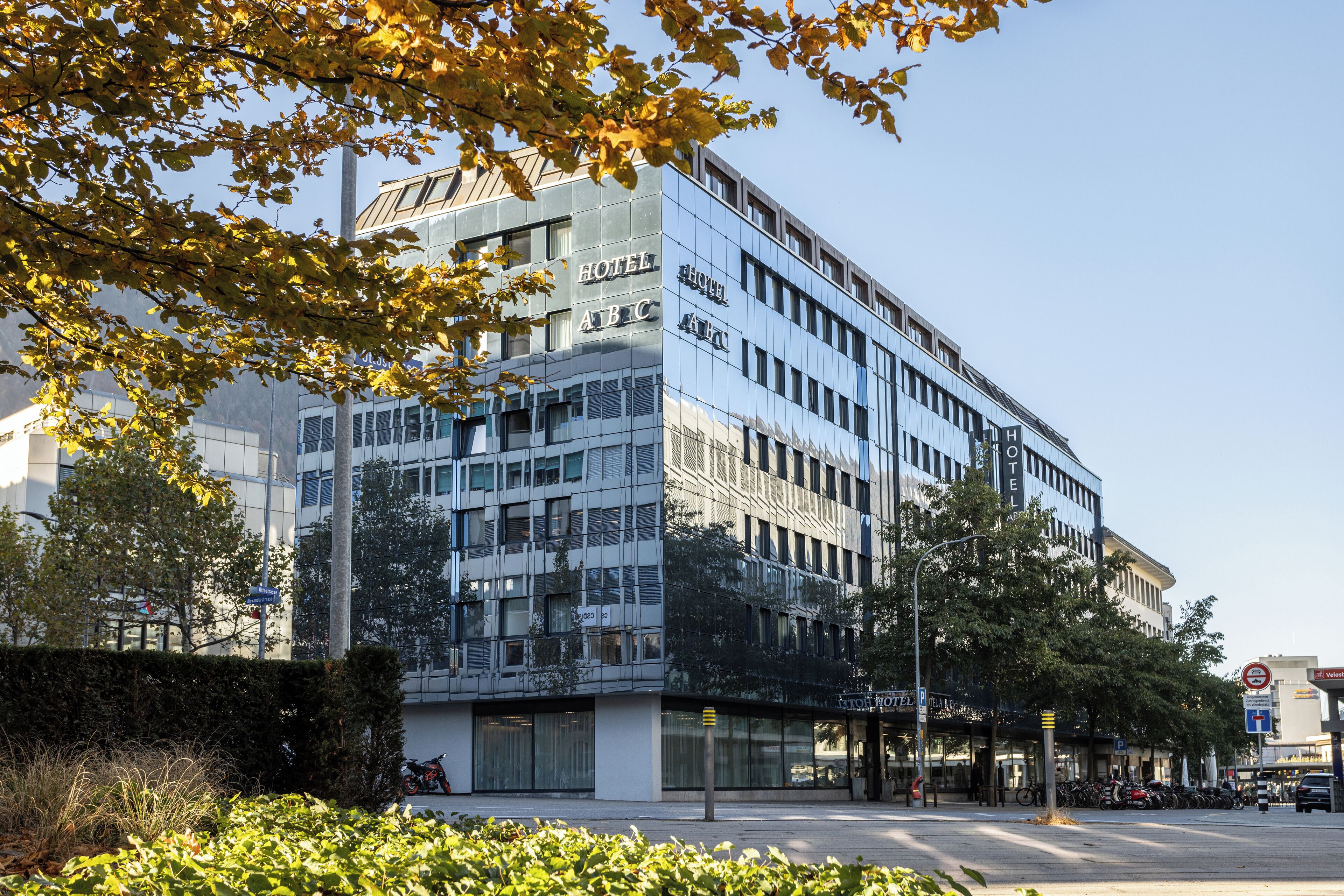 A modern hotel with a glass facade, multiple floors, and a visible entrance.