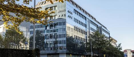 A modern hotel with a glass facade, multiple floors, and a visible entrance.