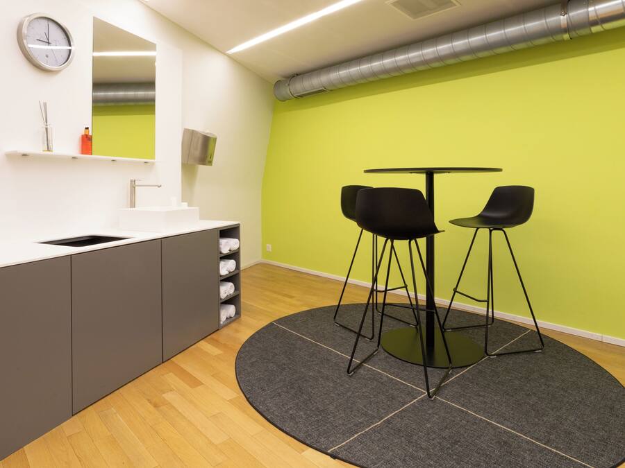 Una cocina moderna con un lavamanos, armarios y una mesa redonda con dos sillas.