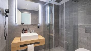 A modern bathroom with a glass-enclosed shower, a wooden vanity with a white sink, and a large mirror above the vanity.