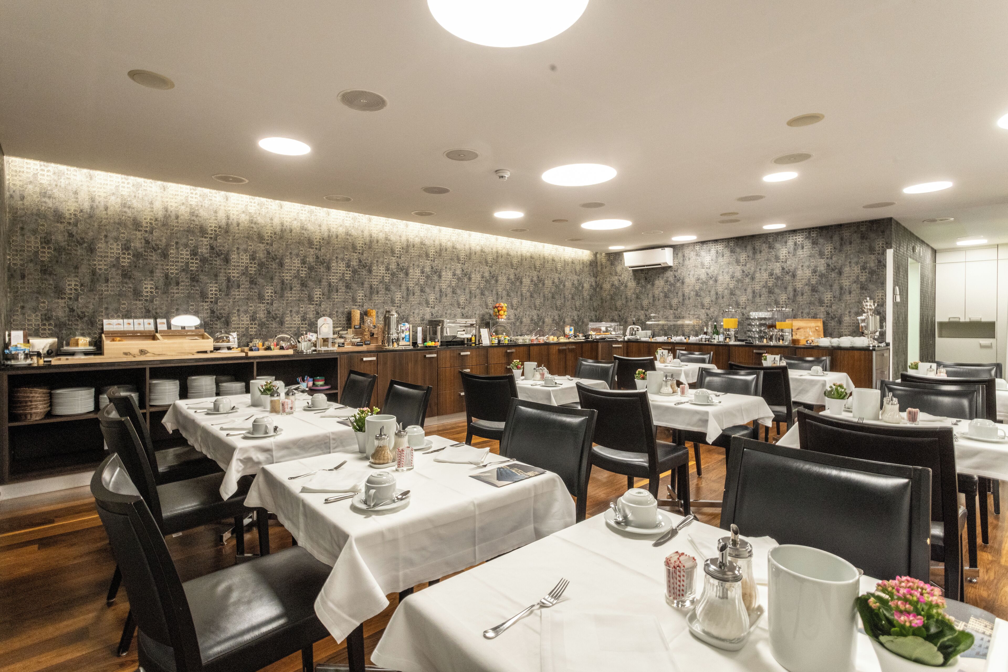 Ein Restaurant mit mehreren Tischen, Stühlen und einer Küchenzeile.
