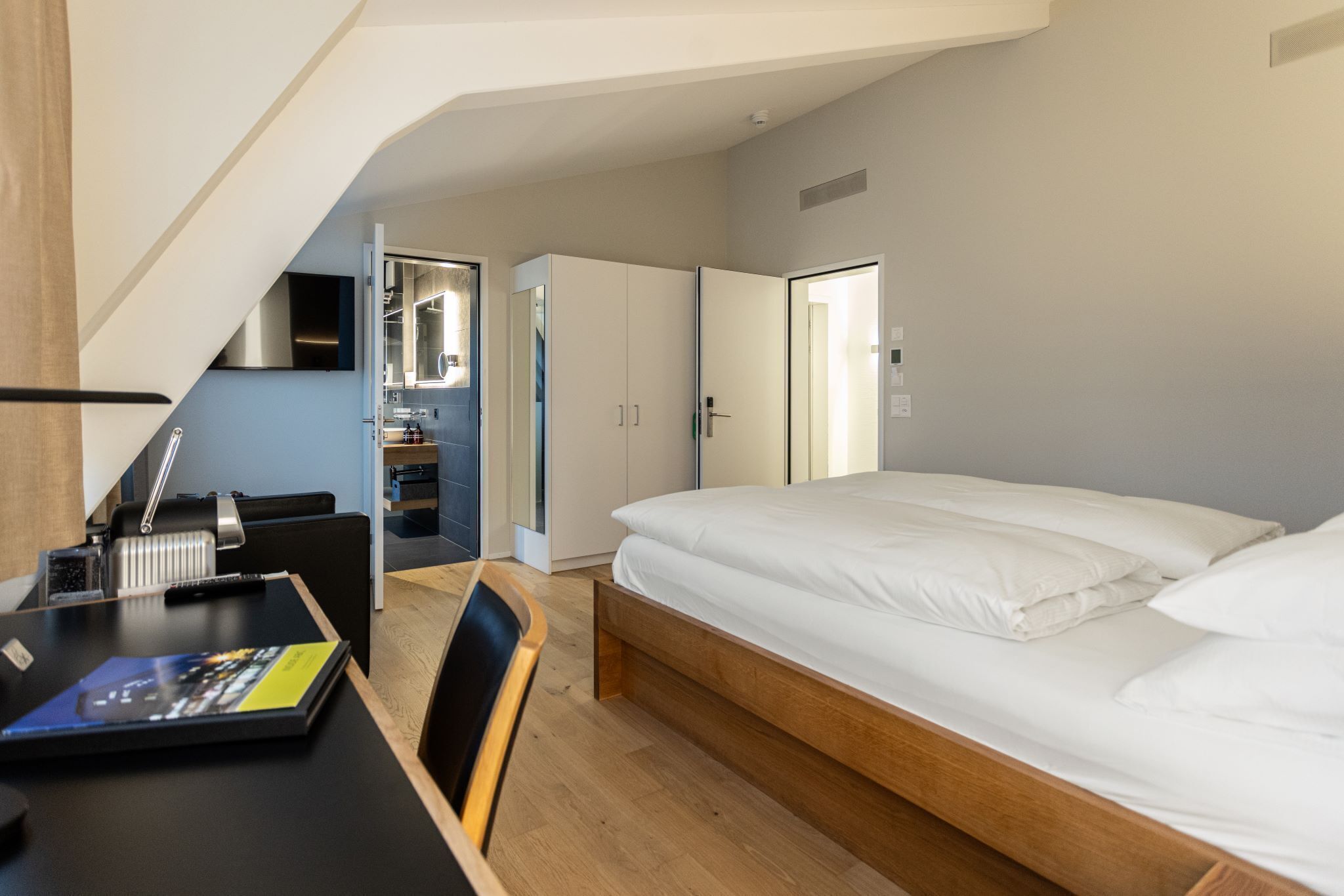 Un dormitorio con cama, escritorio, silla y armario.