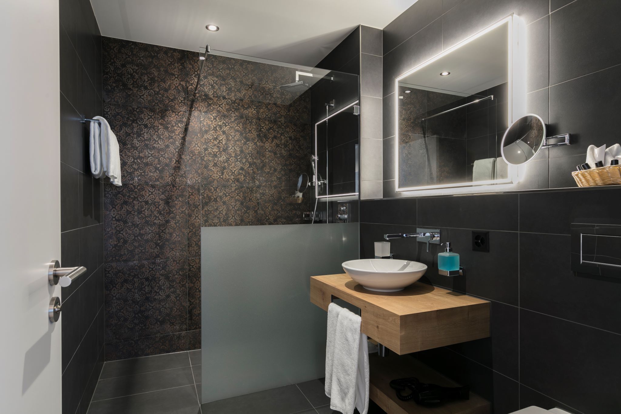 A modern bathroom with a large mirror, a wooden vanity, and a shower area.
