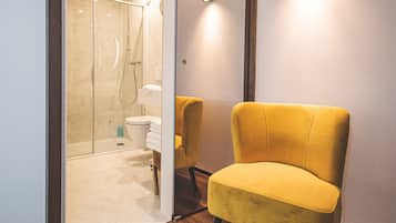 Une salle de bain moderne avec une douche à parois de verre, des toilettes et une chaise jaune.