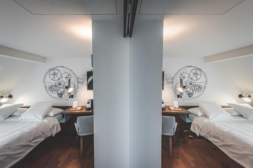 A mirrored room with two beds, a desk, and wall art.