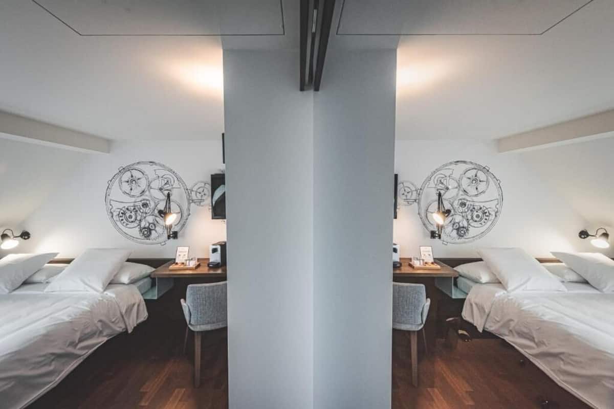 A mirrored room with two beds, a desk, and wall art.