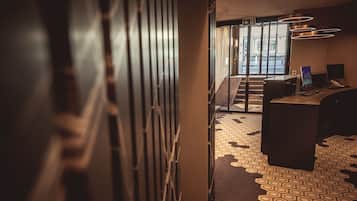 Un vestíbulo de hotel con alfombra de diseño geométrico, un mostrador de recepción y una escalera que conduce a un área exterior.