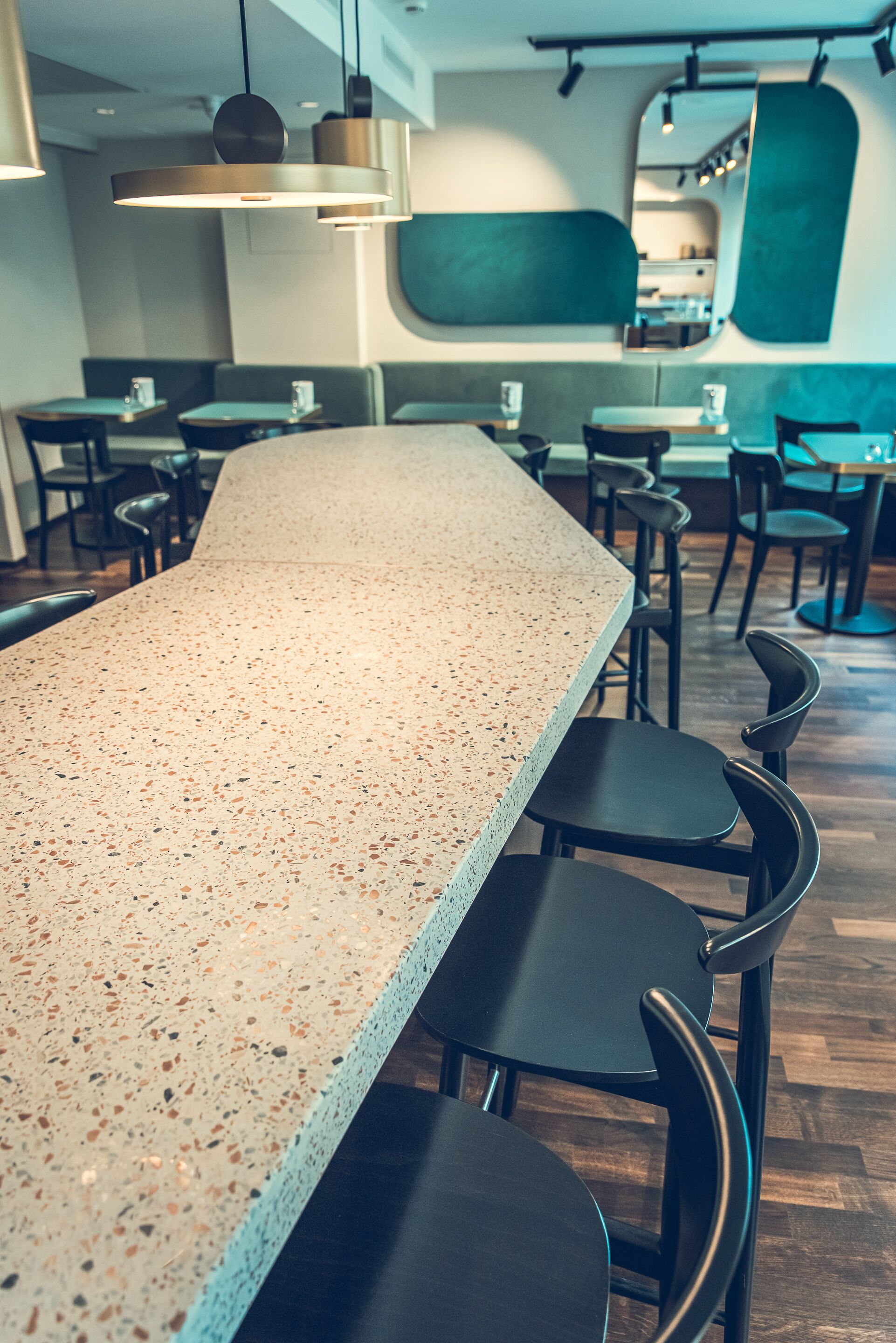 A modern bar area with a speckled countertop, black chairs, and pendant lighting.