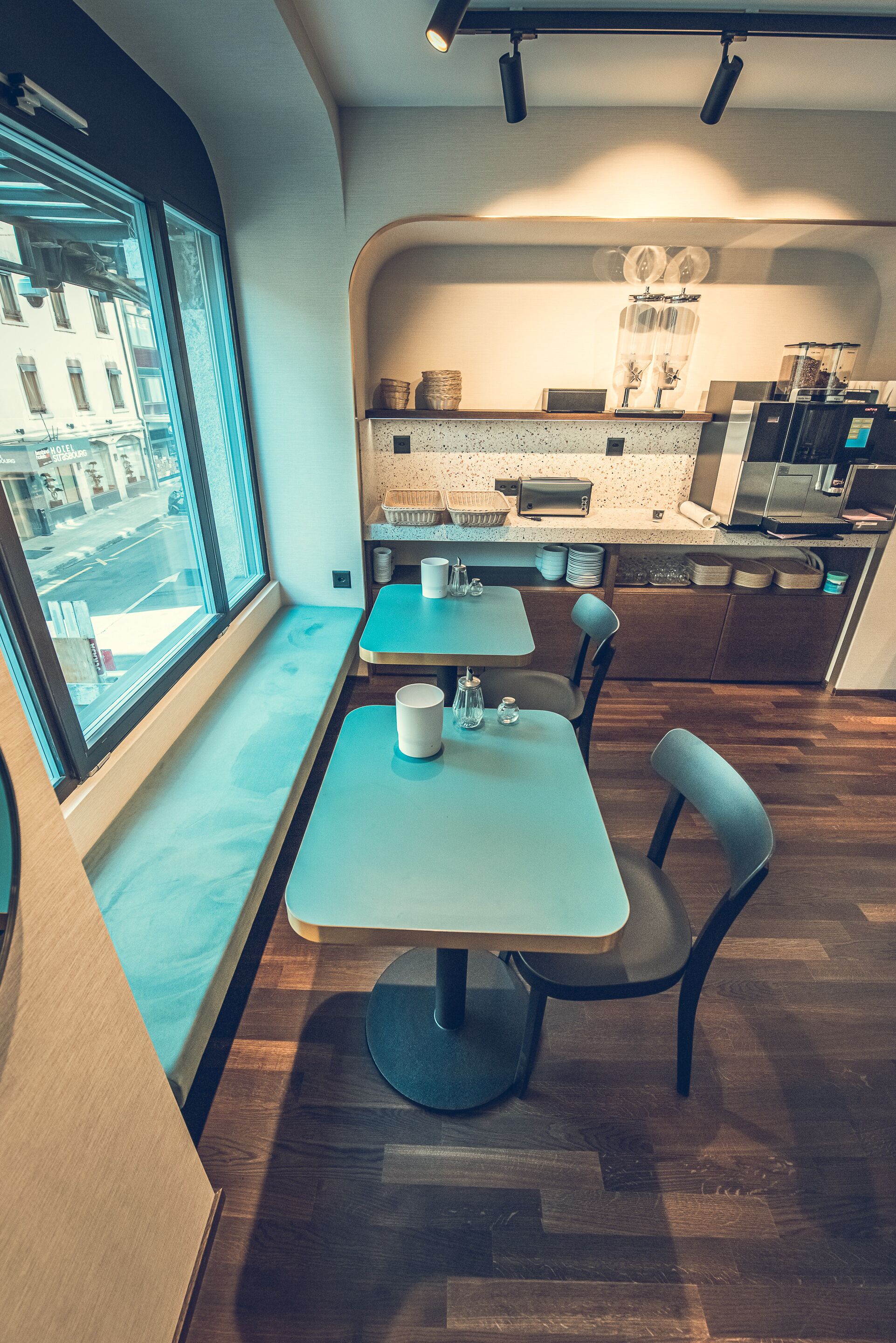 A modern dining area with a window view, a counter with kitchen appliances, and a seating arrangement.
