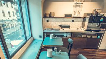Un espace repas moderne avec vue sur l’extérieur grâce à une fenêtre, un comptoir équipé d’appareils de cuisine et un coin salon.