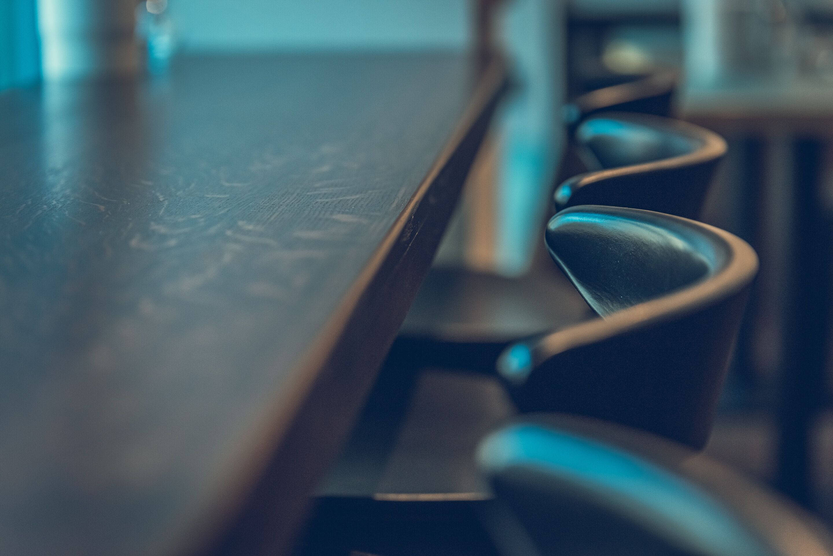 A close-up of a wooden table with a dark finish and a metal chair with a curved backrest.