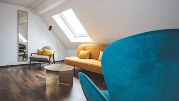 Un dormitorio tipo loft moderno con tragaluces, una mesa redonda, un sofá y un sillón azul.