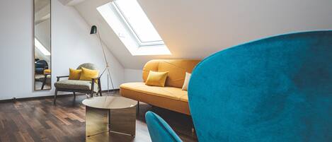 Un dormitorio tipo loft moderno con tragaluces, una mesa redonda, un sofá y un sillón azul.
