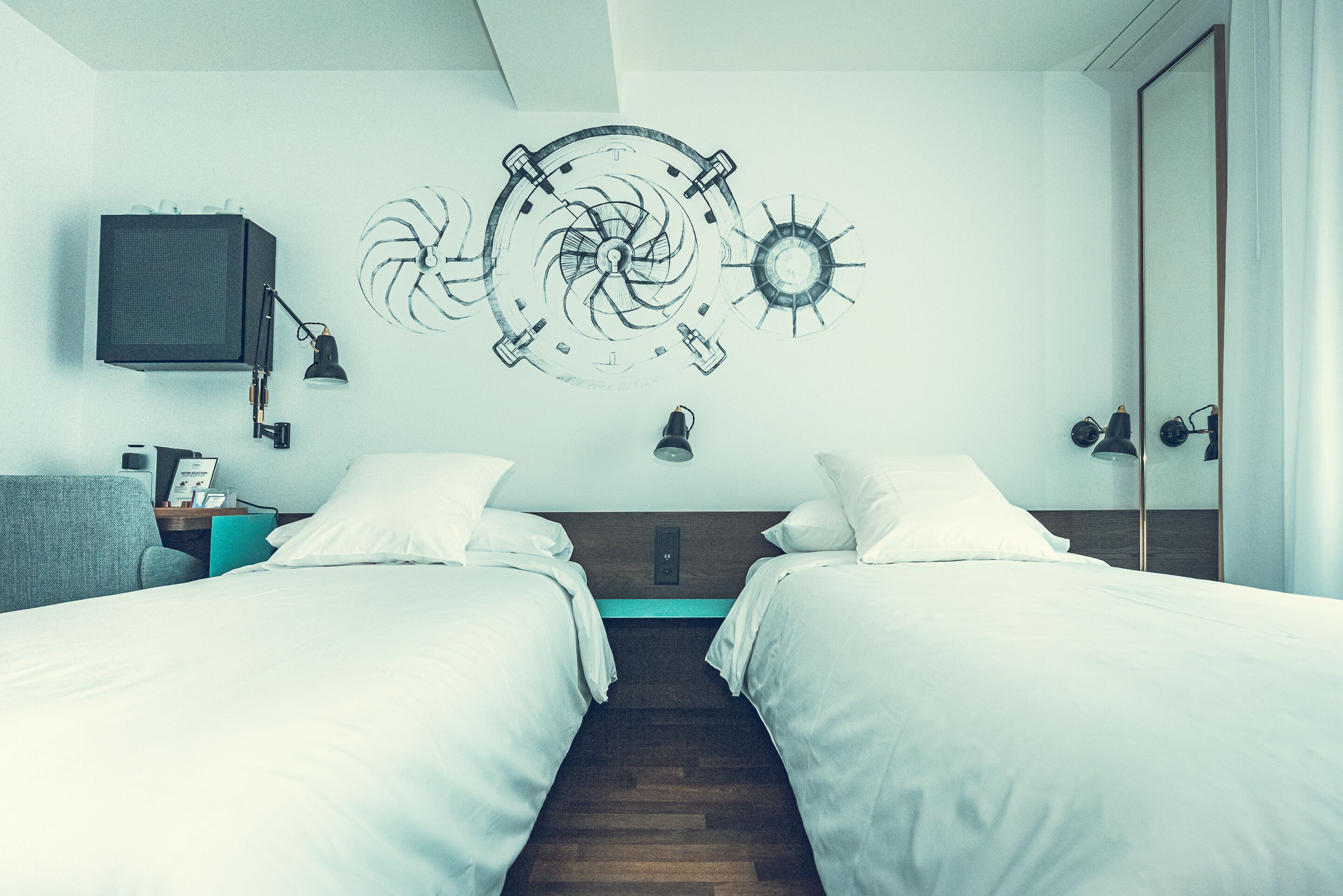 Habitación de hotel con dos camas, un reloj de pared, un televisor y una mesita de noche con lámpara.