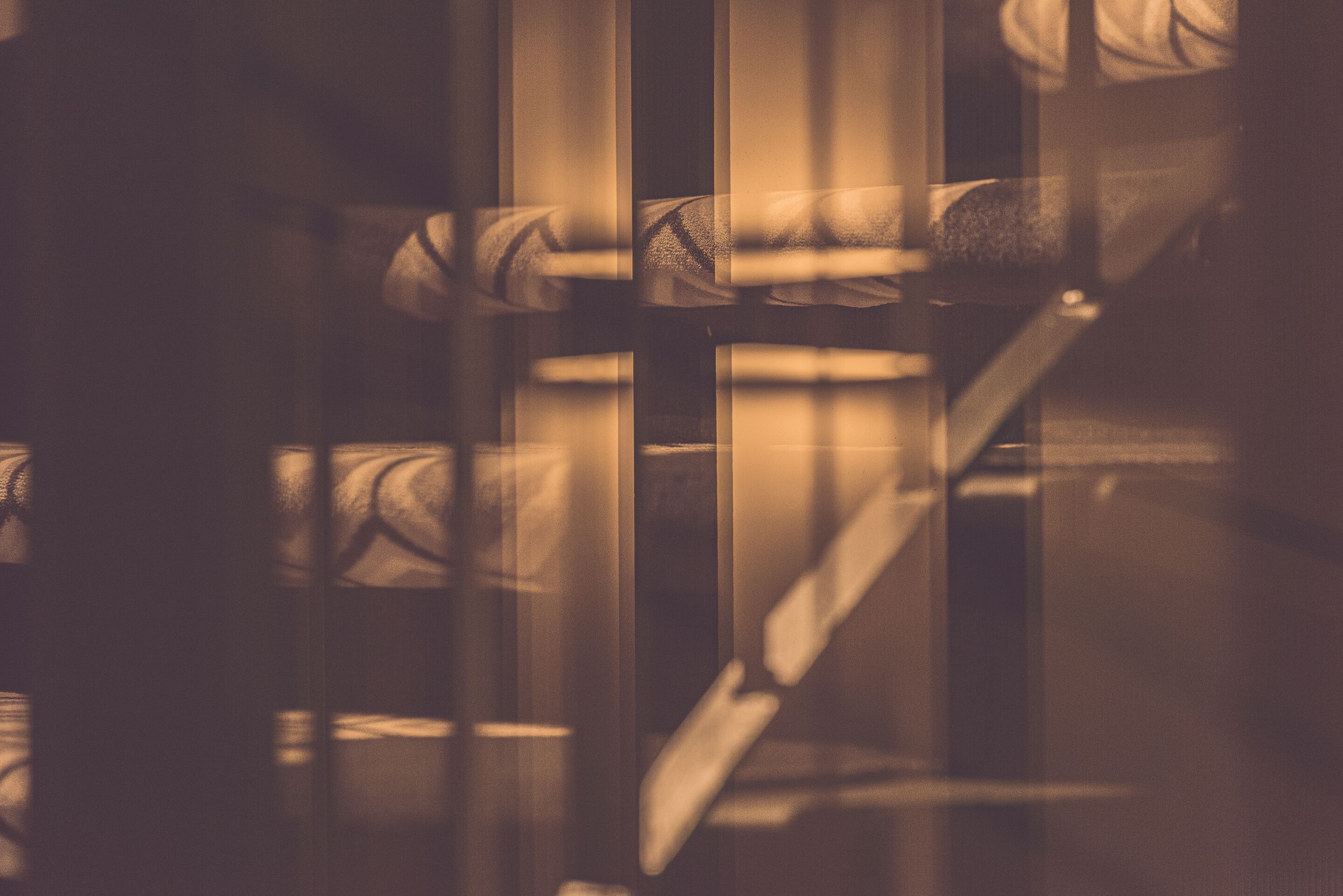 A close-up of a staircase with a handrail and steps, viewed through a patterned glass door.