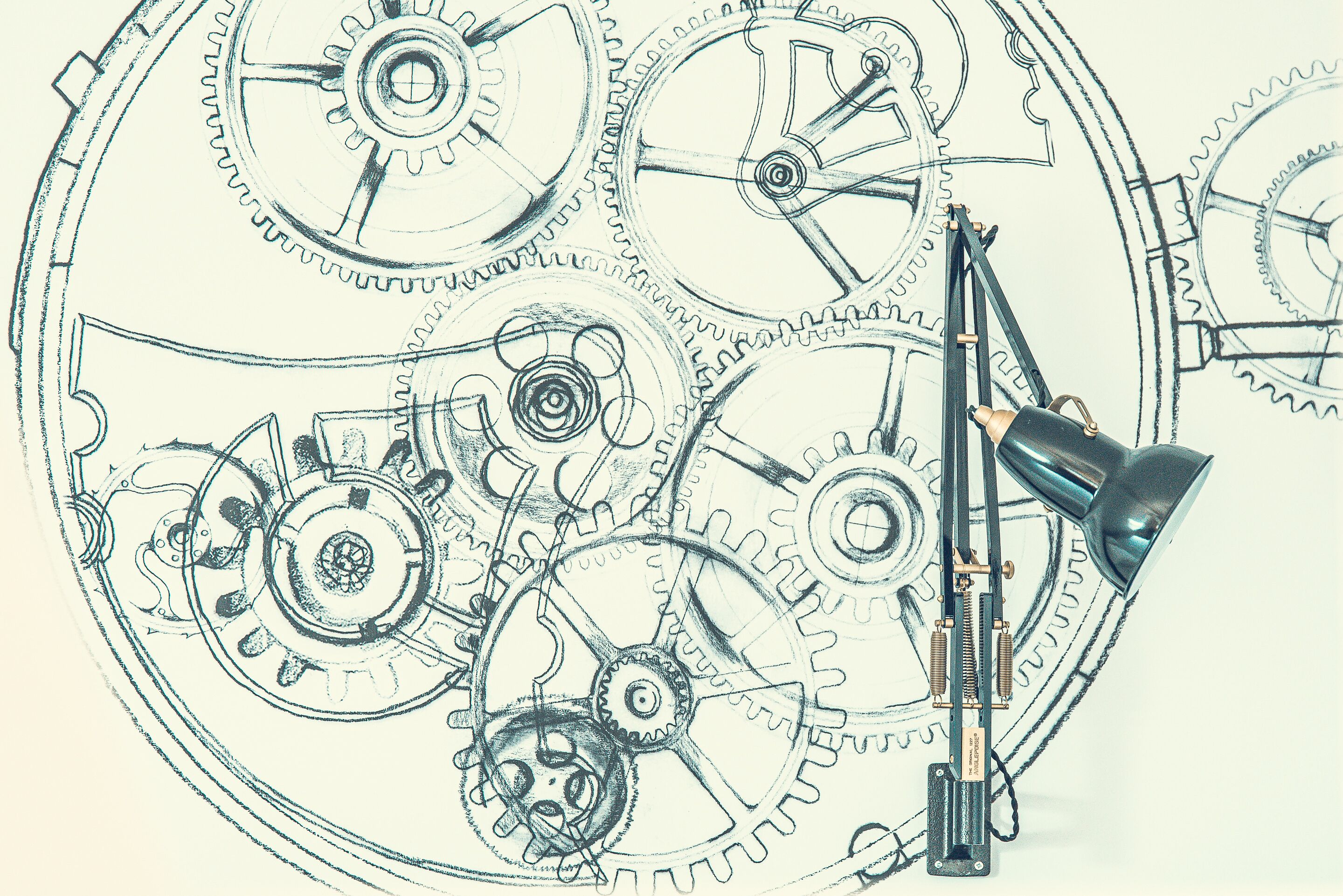 A detailed mechanical drawing of interlocking gears with a drafting lamp positioned to the right.