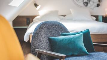 A modern bedroom with a loft-style ceiling, a bed with white linens, and teal pillows.