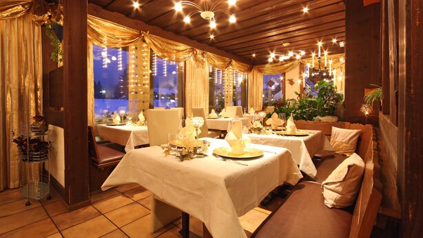 Un restaurante con interiores de madera, manteles blancos y una atmósfera iluminada por velas.