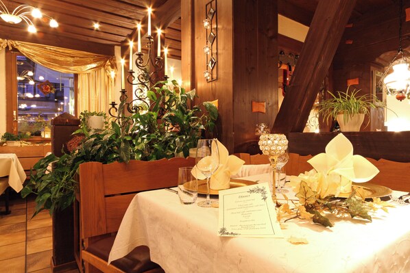 A dining table set with a menu, a candle, and a potted plant. - Bernerhof Swiss Quality Hotel (Kandersteg)