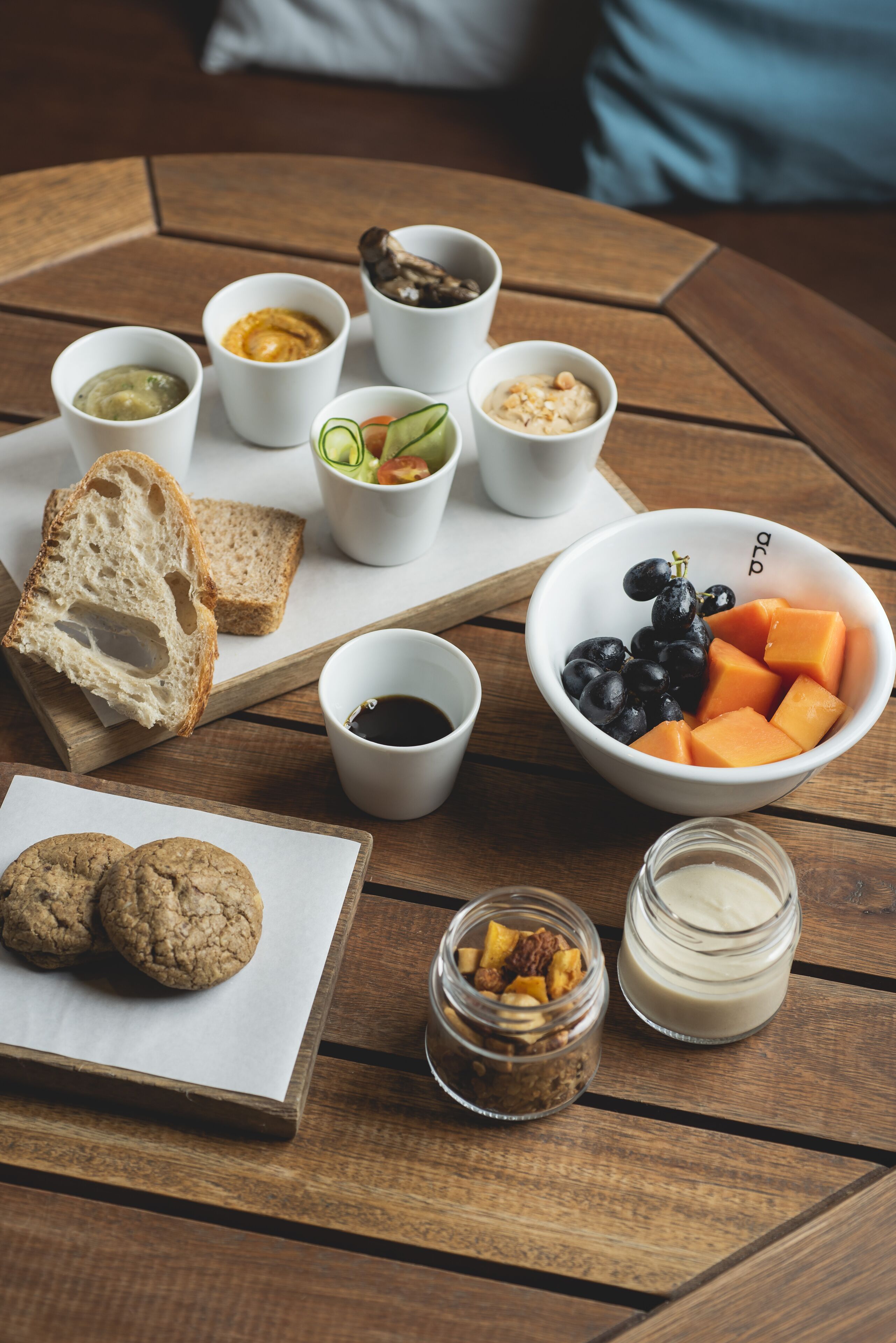 Una mesa de madera con diversas comidas como pan, queso, uvas y galletas.