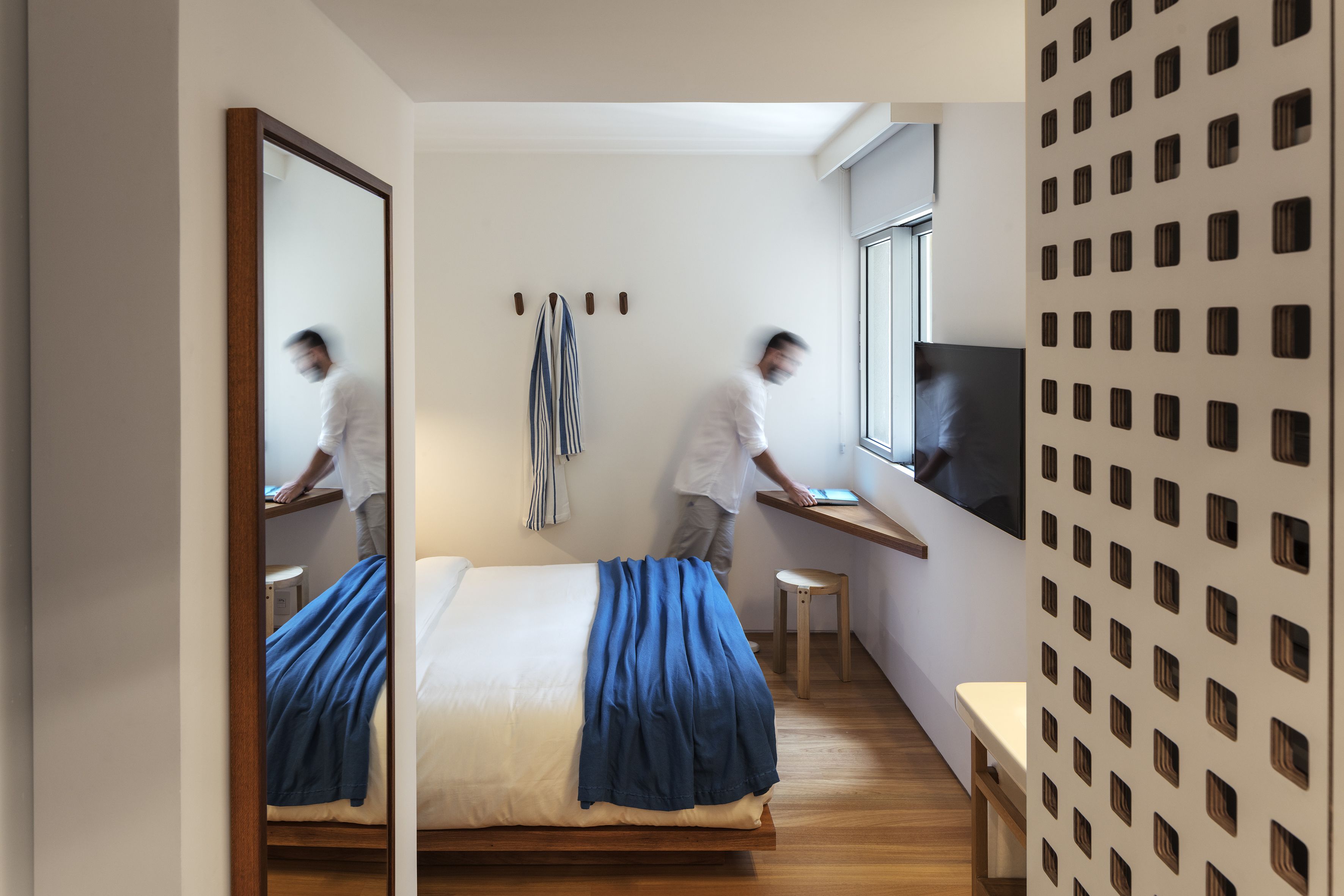 A modern bedroom with a large bed, a desk, and a TV.