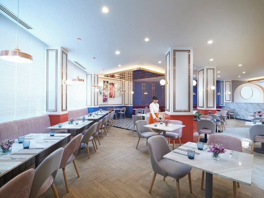 A restaurant with multiple dining tables and chairs, a waitress, and a counter area.