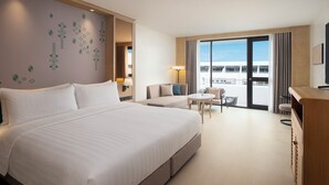 Une chambre d’hôtel avec un grand lit, un canapé, une petite table, une chaise et un balcon avec vue.