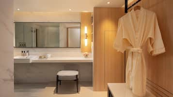 A modern bathroom with a marble sink, a mirror, a robe hanging on the wall, and a wooden vanity.