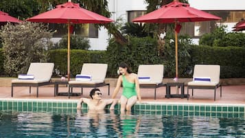 A poolside area with lounge chairs and red umbrellas.