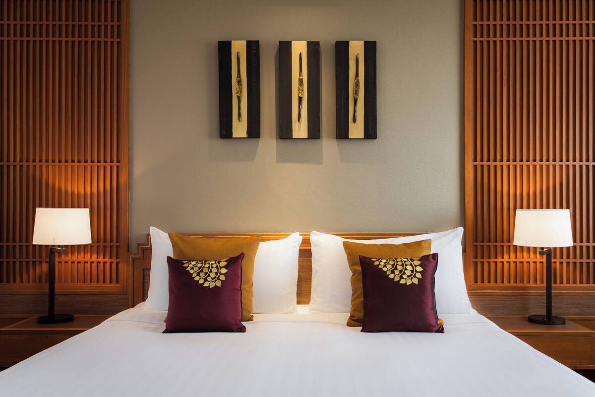 Una habitación de hotel con una cama grande, dos lámparas de noche y una obra de arte colgada en la pared sobre la cama.
