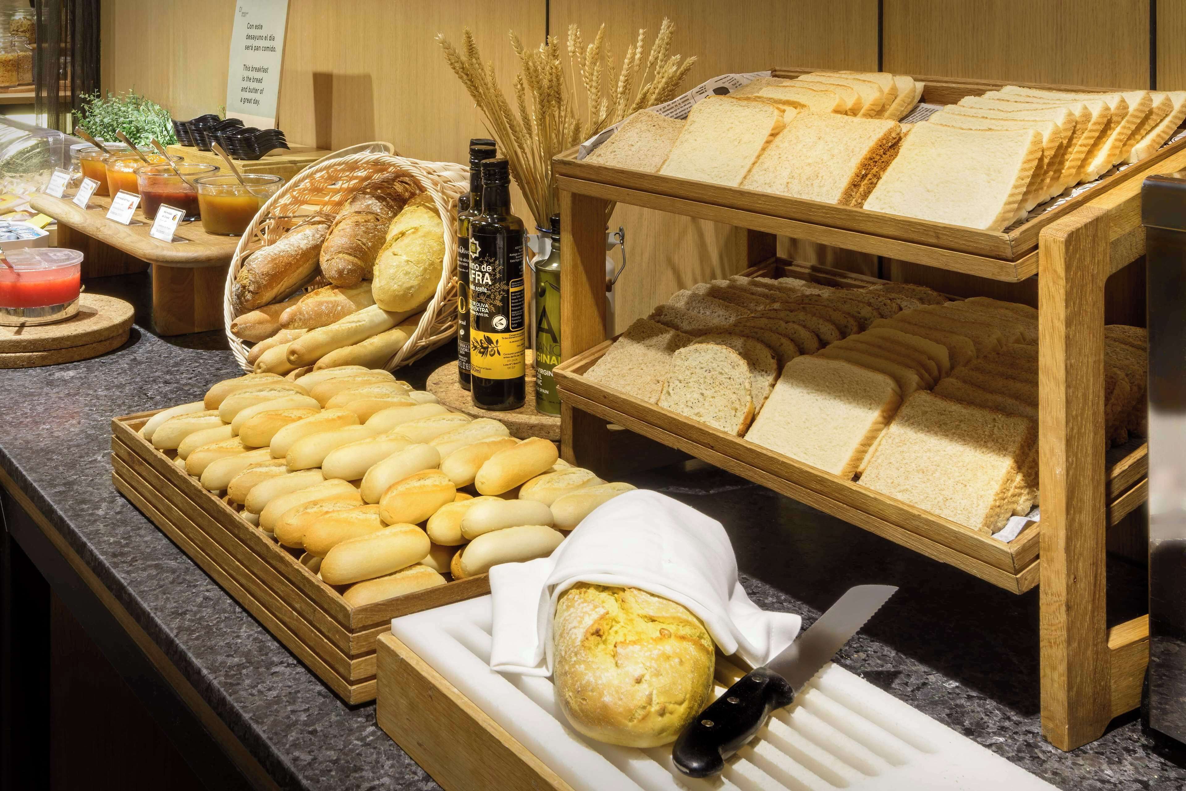 Un bufé de desayuno con panes, bollería y bebidas variadas.