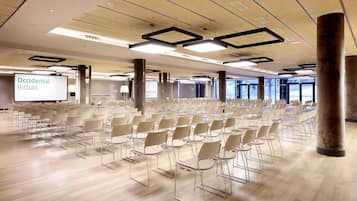 A conference room with rows of chairs, a projector screen, and a large window.