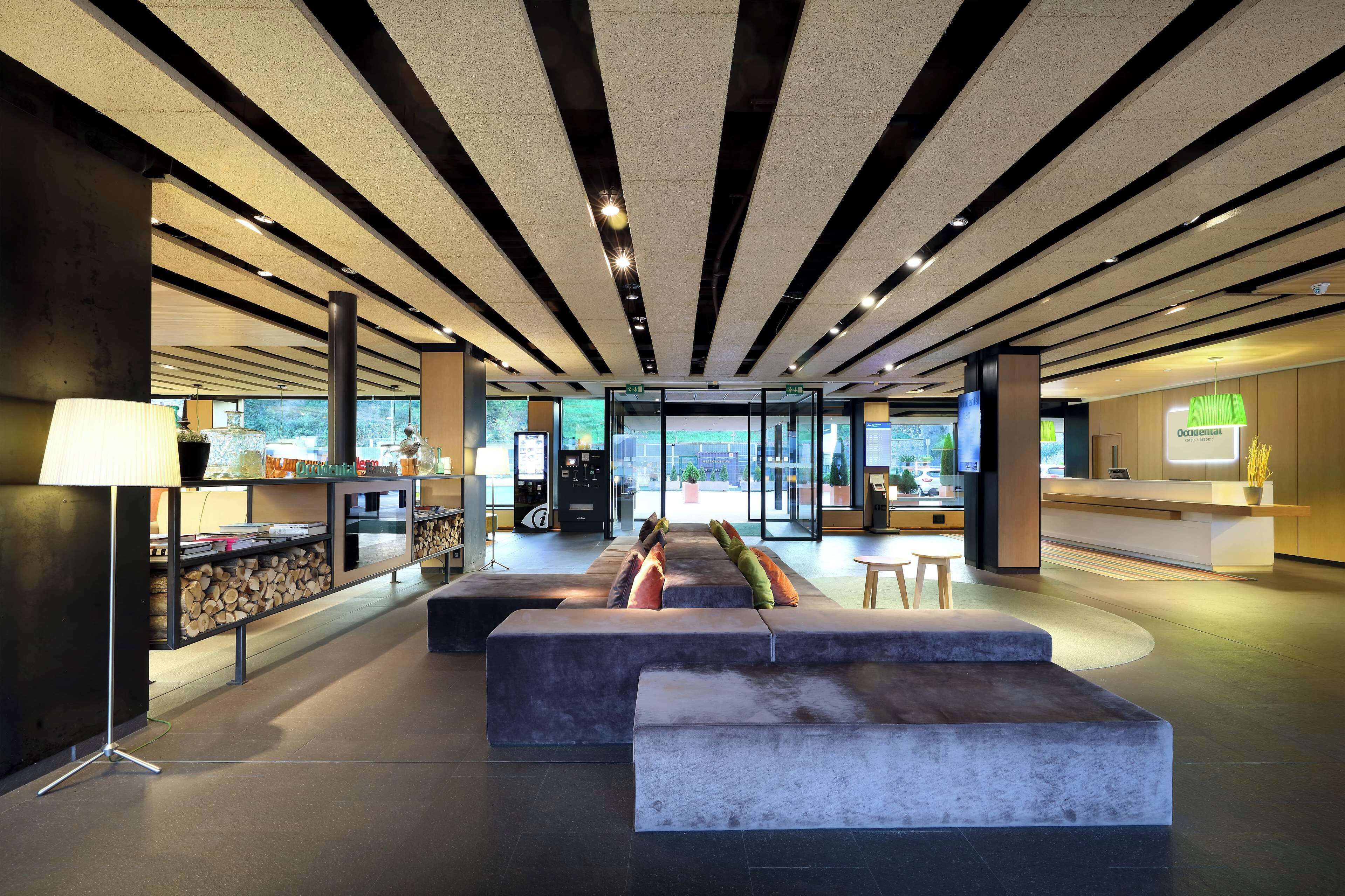 A modern lobby with a reception desk, seating area, and a large window offering a view of the outdoors.