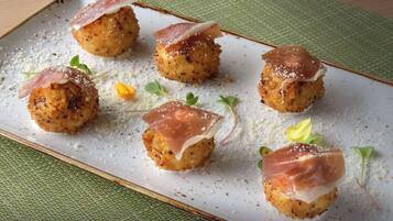 A plate of food with breaded balls topped with prosciutto and garnished with microgreens.