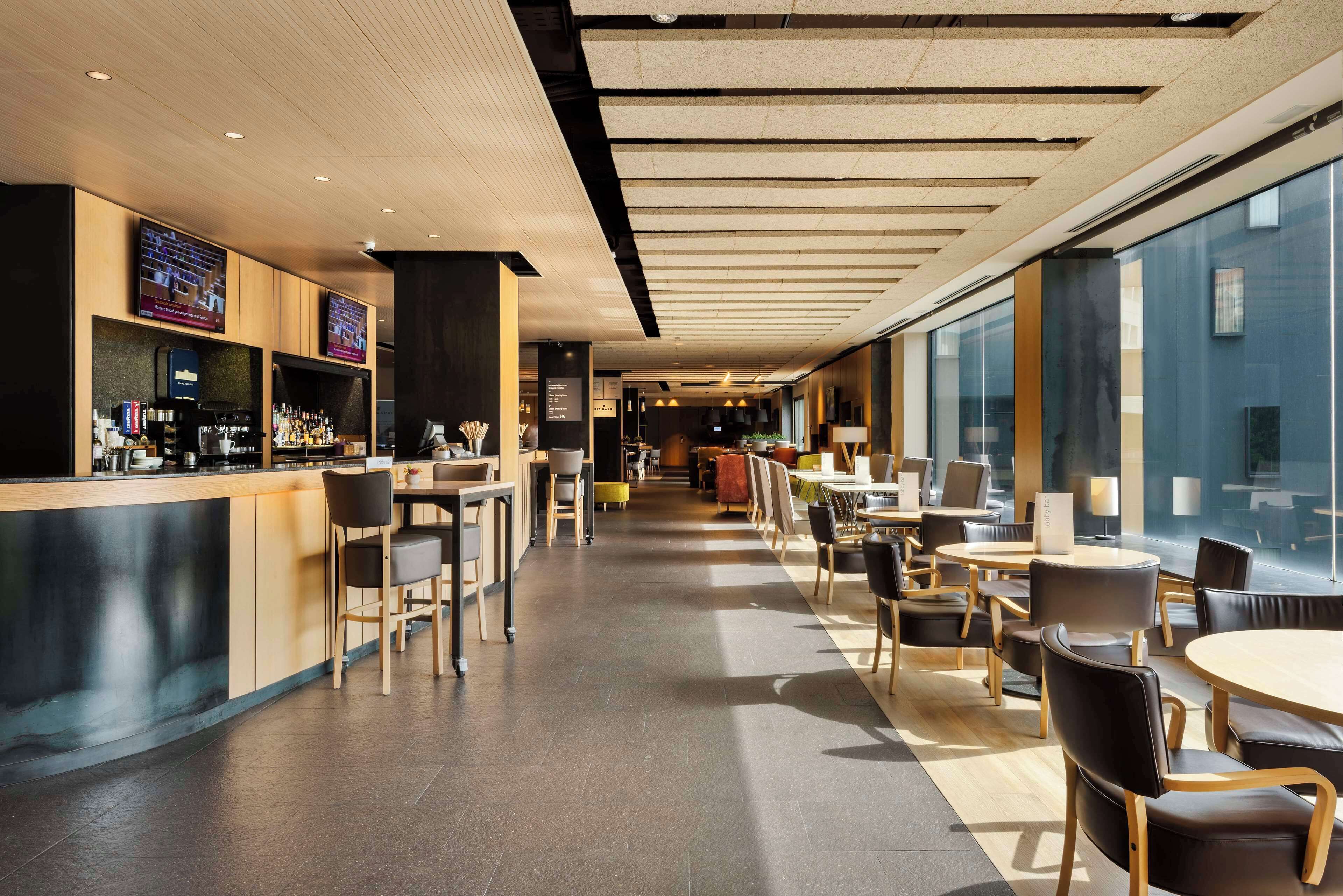 A modern cafe with a bar area, seating arrangements, and large windows.