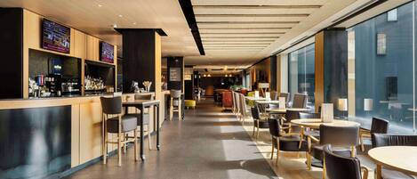 A modern cafe with a bar area, seating arrangements, and large windows.