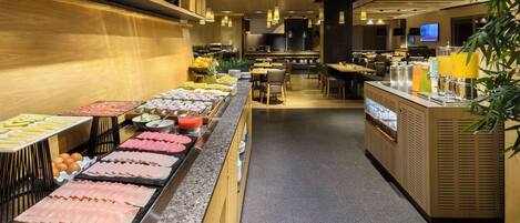 A buffet area with various food options and a seating area with tables and chairs.