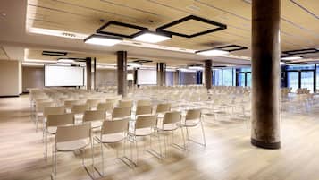 A conference room with rows of chairs, a large screen, and a pillar.