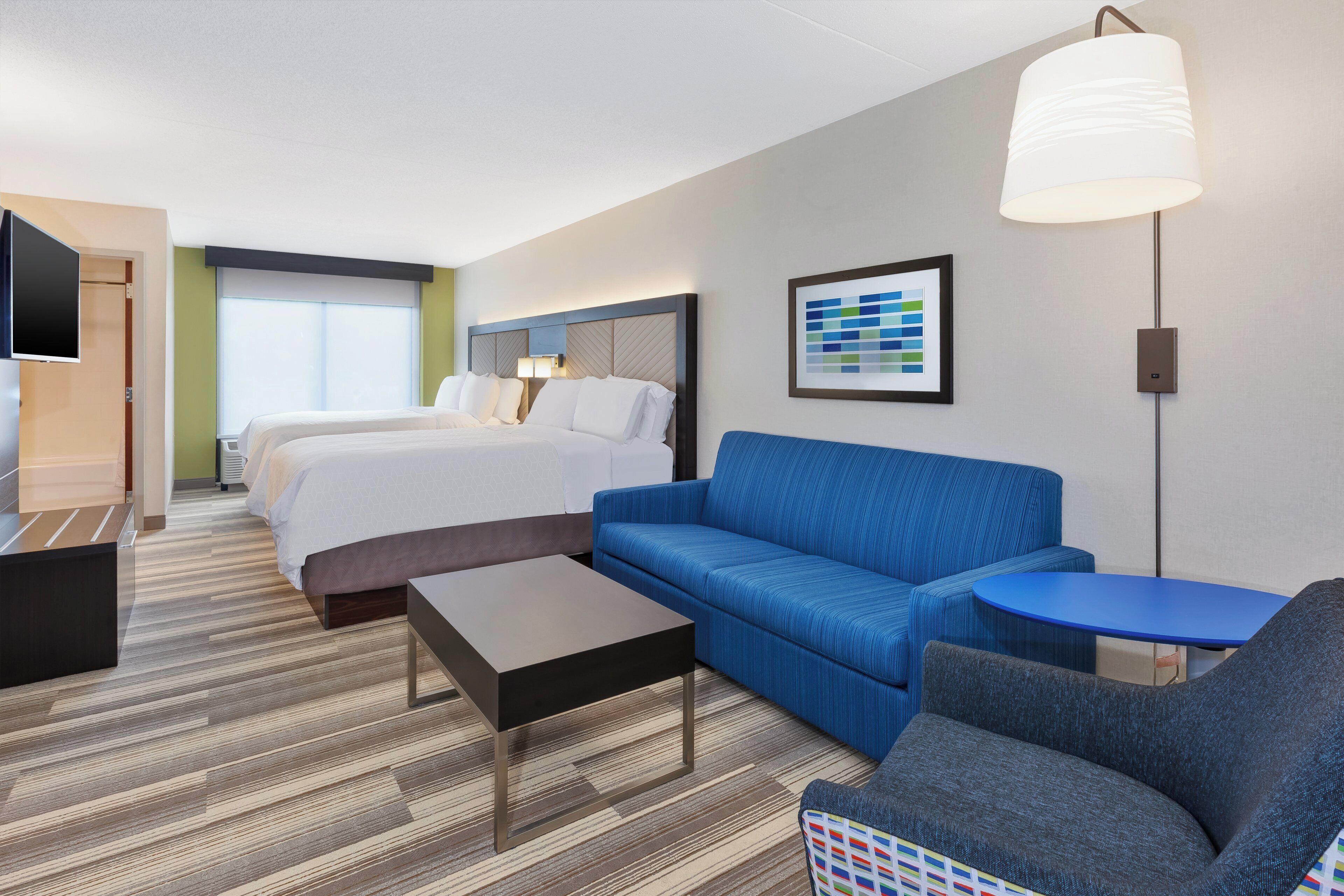 Une chambre d’hôtel avec un lit, un canapé, une petite table et une lampe.