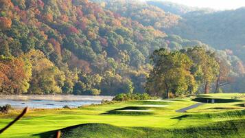 Enjoy a serene golfing experience surrounded by rolling hills and a tranquil body of water.
