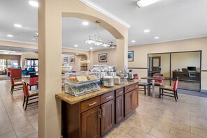 A hotel breakfast area with a buffet counter, seating area, and a large mirror. - Comfort Inn Corsicana East (Corsicana)