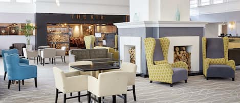 A spacious lobby with a fireplace, seating area, and a restaurant named "THERI B".