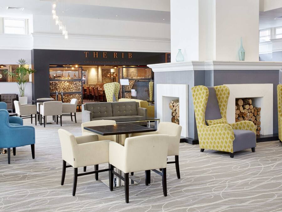 A spacious lobby with a fireplace, seating area, and a restaurant named "THERI B".
