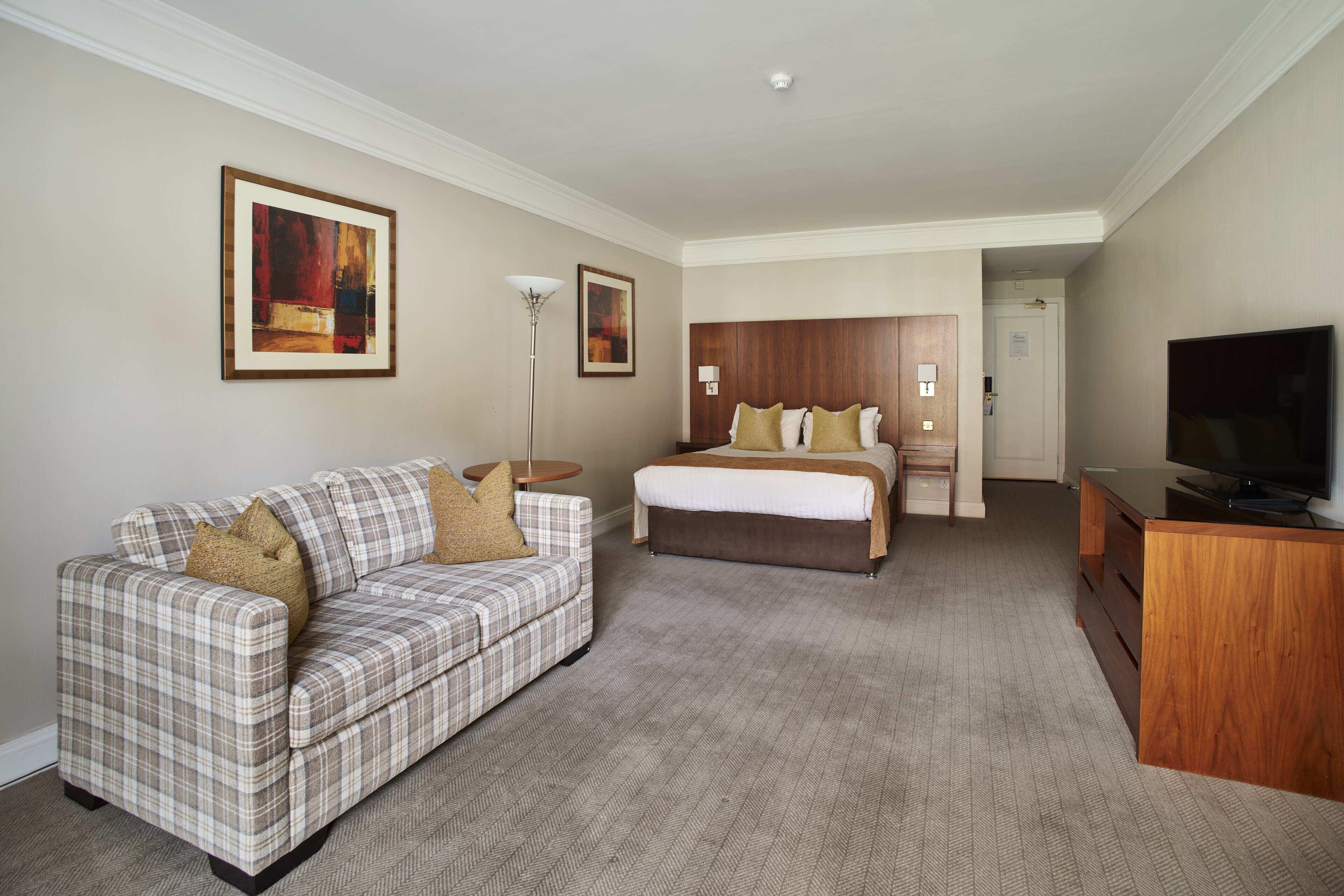 Une chambre d’hôtel avec un lit, un canapé, un bureau et une télévision.
